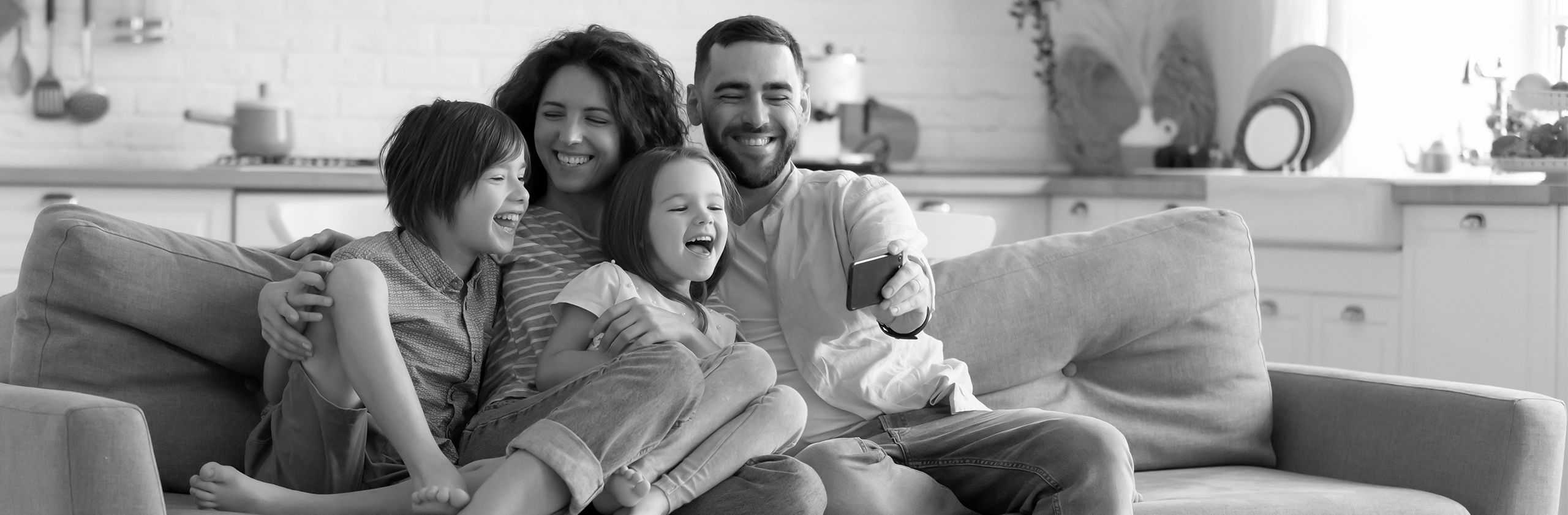 parents with two kids on a couch taking a selfie